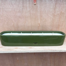 Green candle holder with candles on a wooden surface